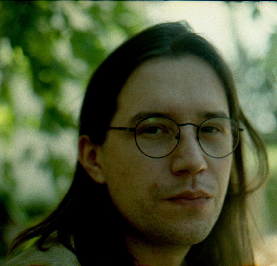 mężczyzna w długich włosach, zdjęcie portretowa Piotra Fronia