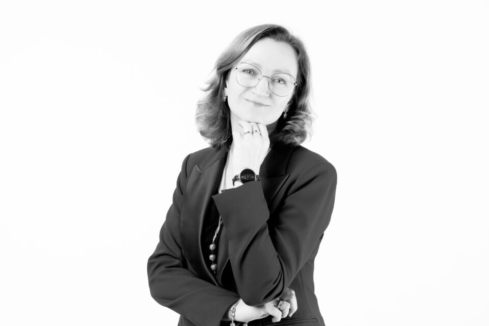 Kobieta w okularach ma falujące się włosy.